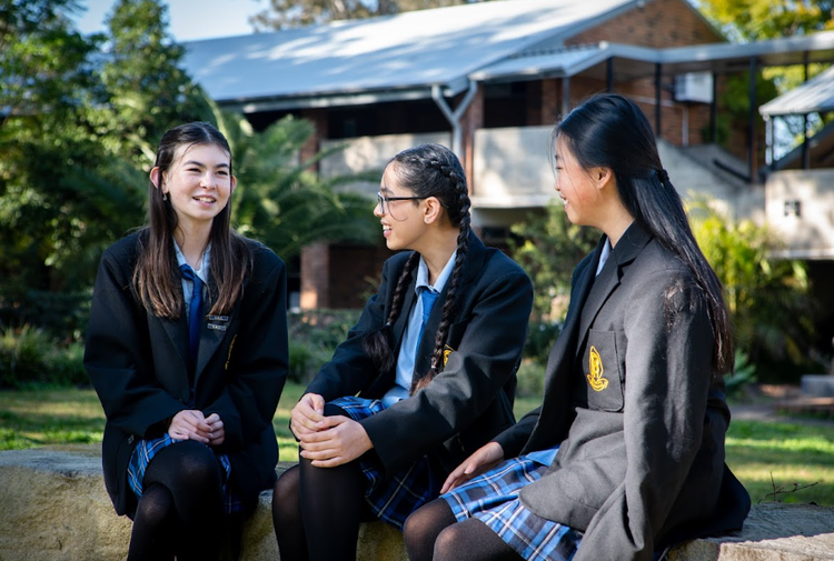 Three female students talking while seated in the playground